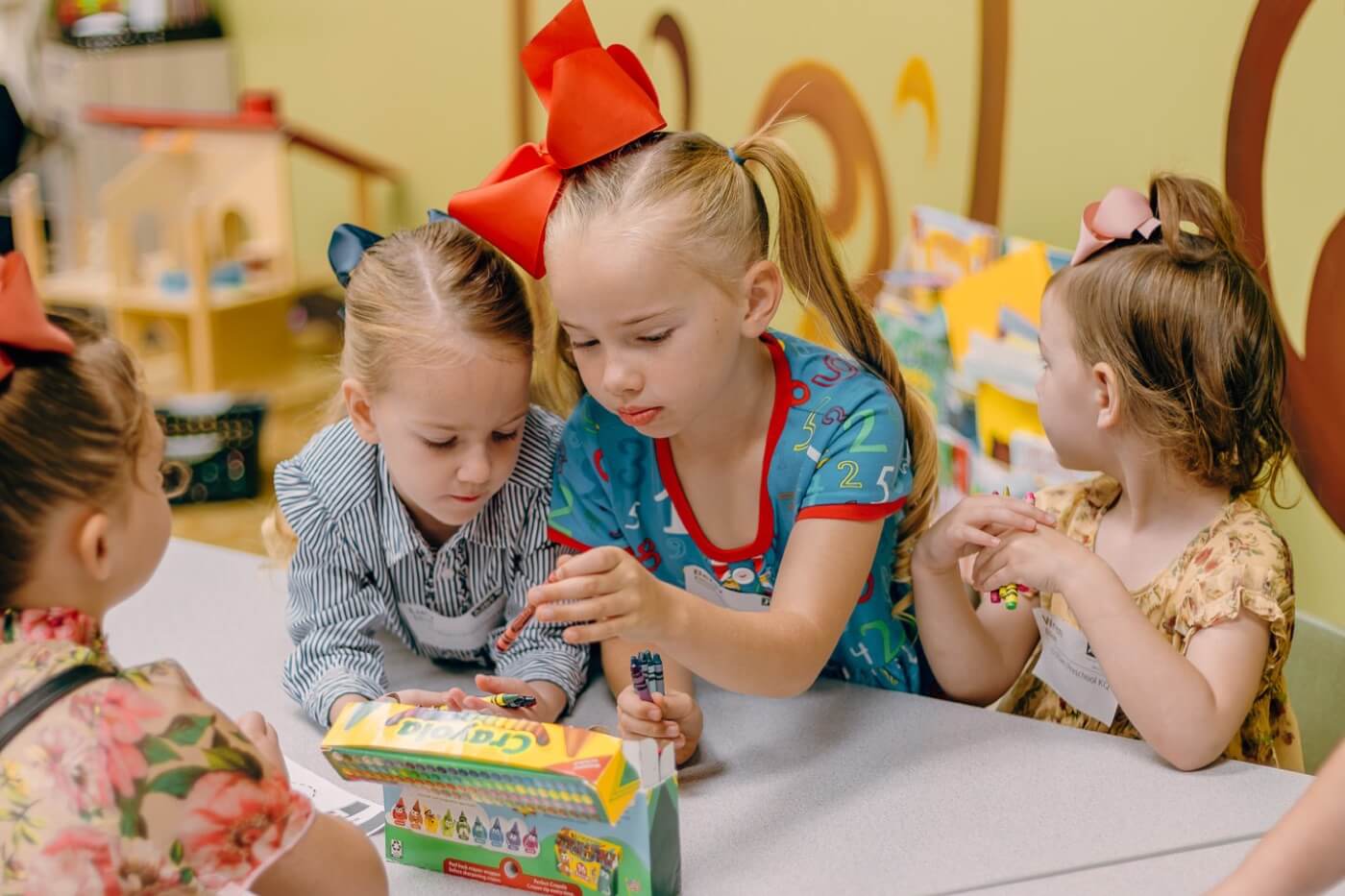 Preschoolers sharing crayons around a classroom table at ACA Daycare